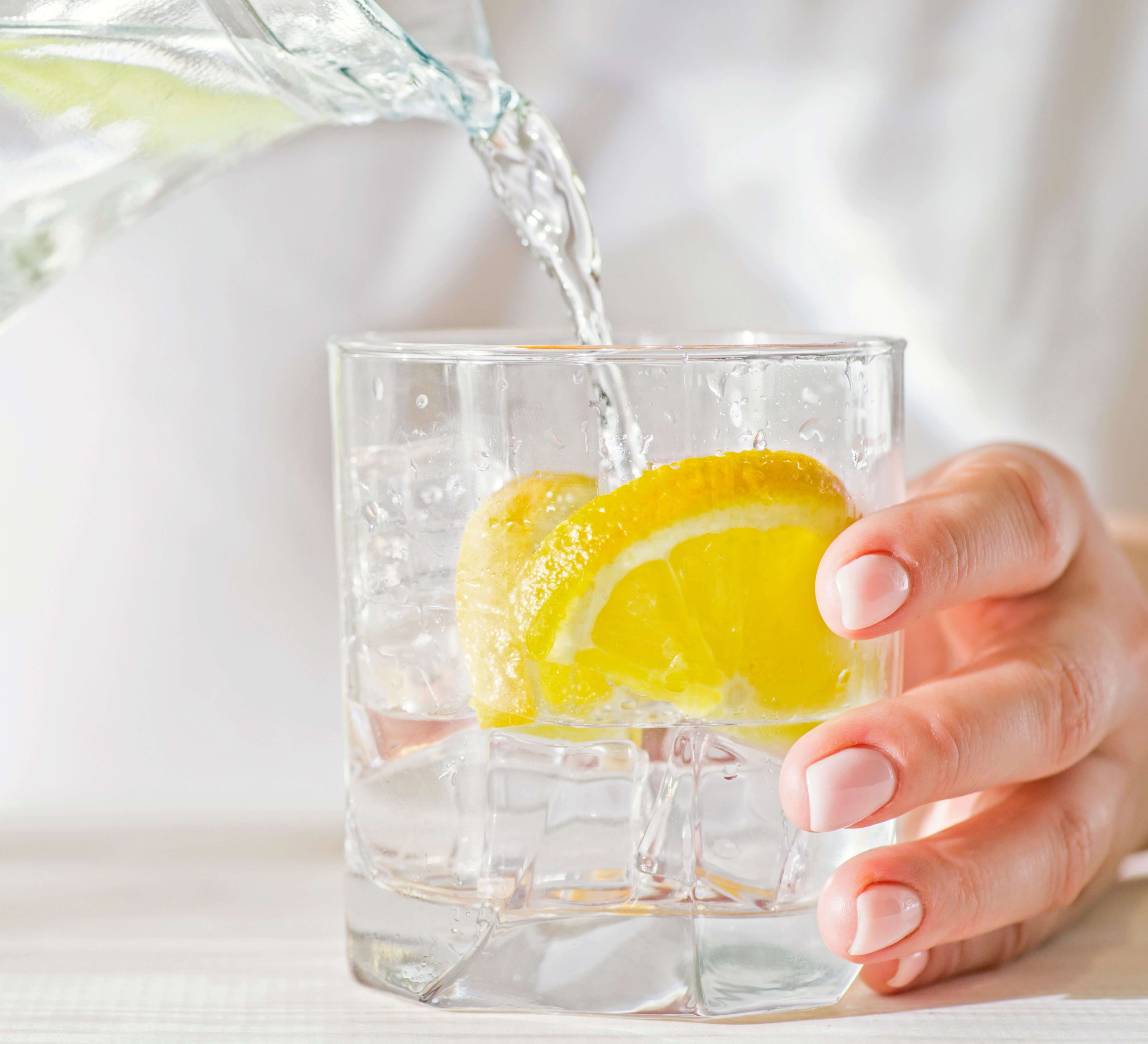 hand holding glass of lemon water
