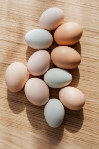 set of multicolored raw eggs on wooden table