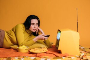 woman in yellow long sleeve shirt watching tv in bed