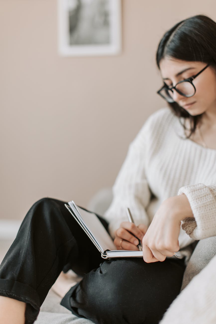 body positive journal prompts crop young woman writing schedule in diary on sofa