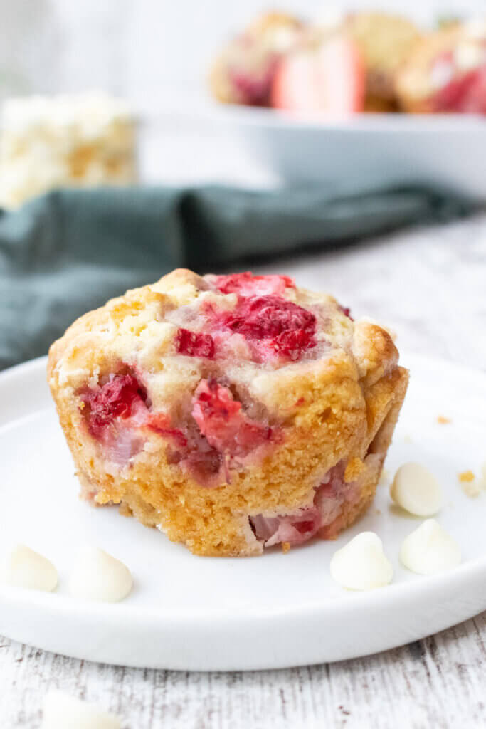 side view of white chocolate and strawberry muffins on white plate