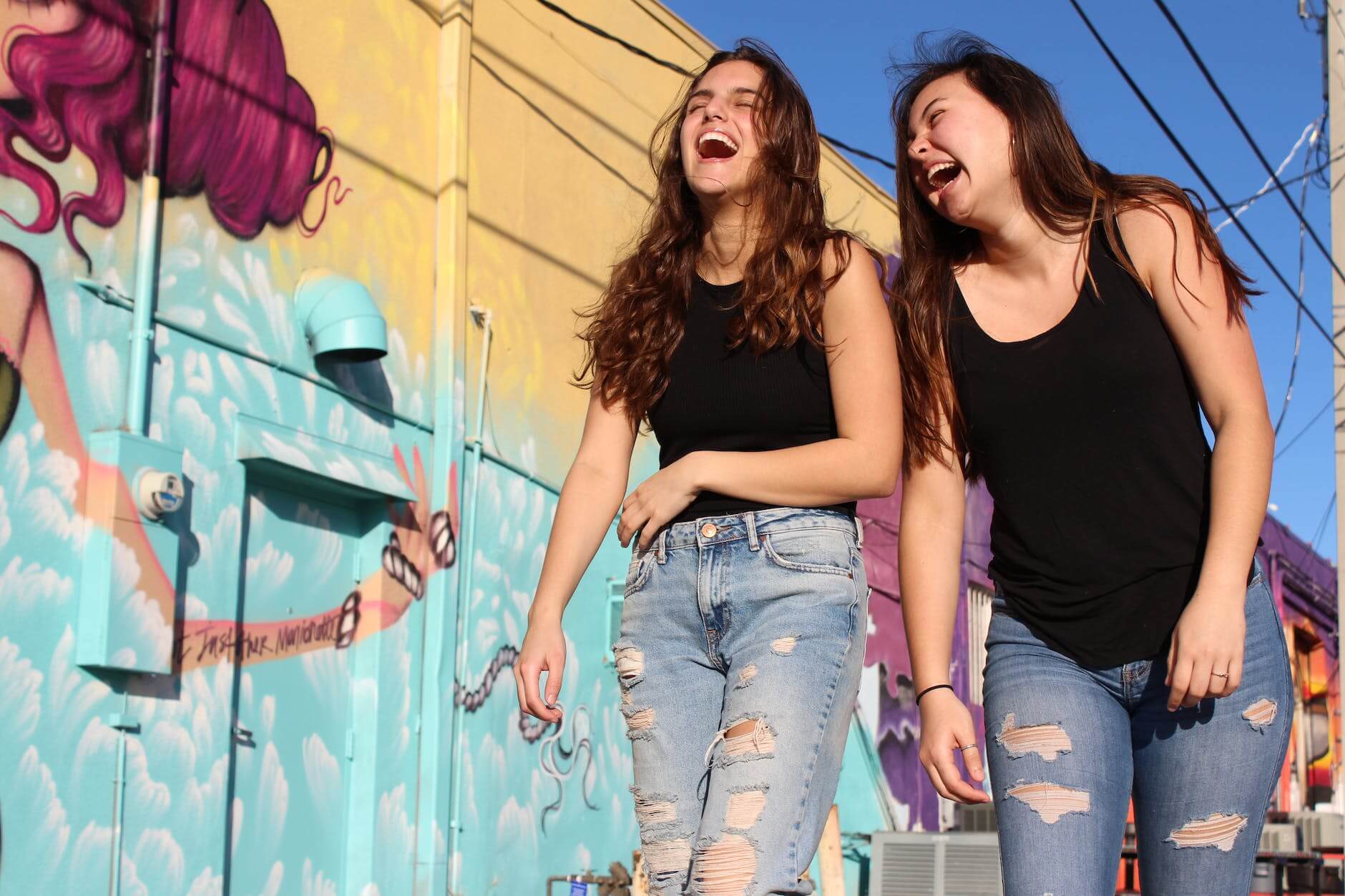 photo of two laughing women walking past graffiti wall for dry January