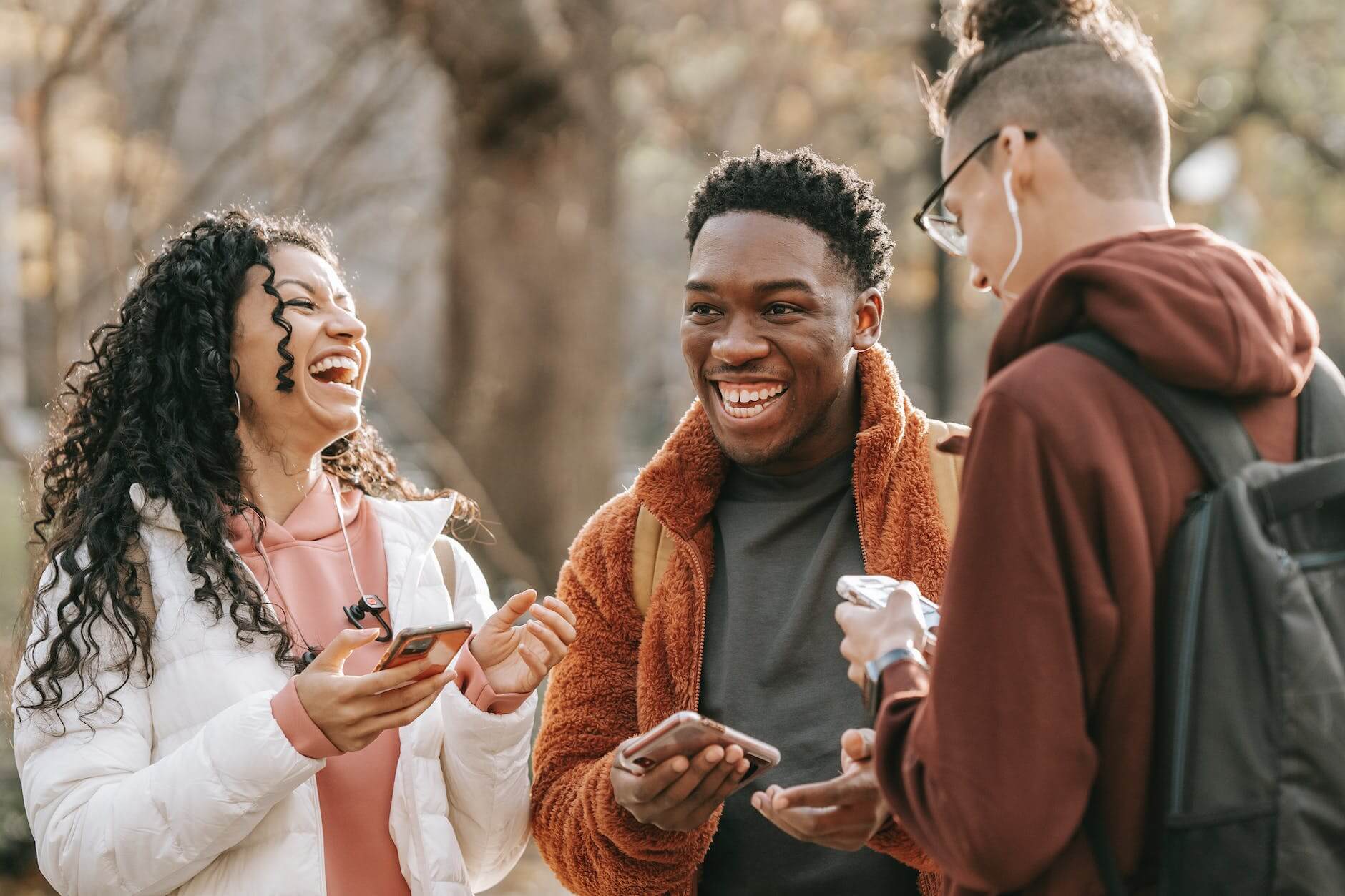 laughing diverse friends with smartphones in park for dry January