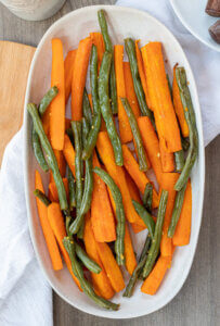 Roasted green beans and carrots in a white bowl