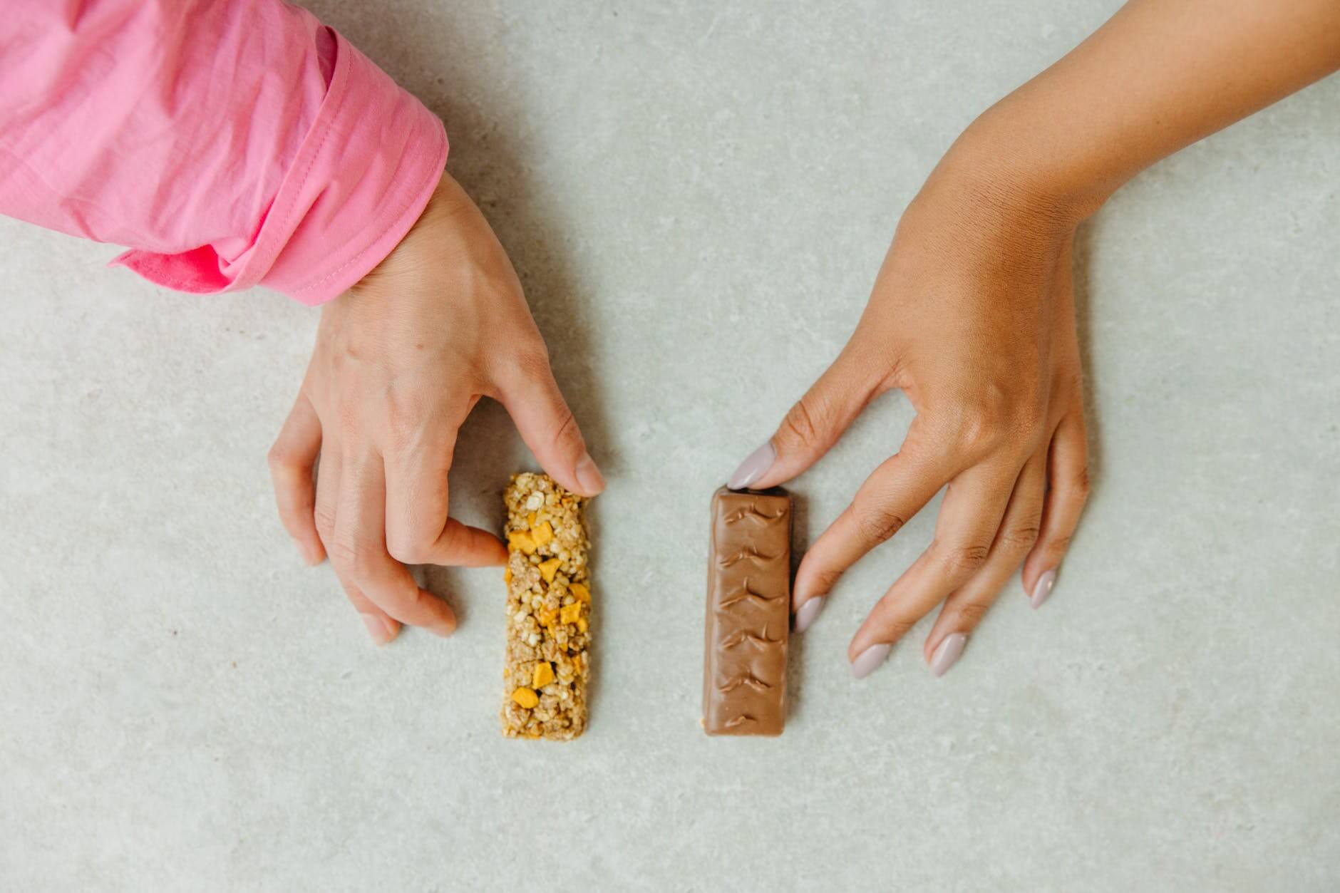 person holding a chocolate bar and granola bar