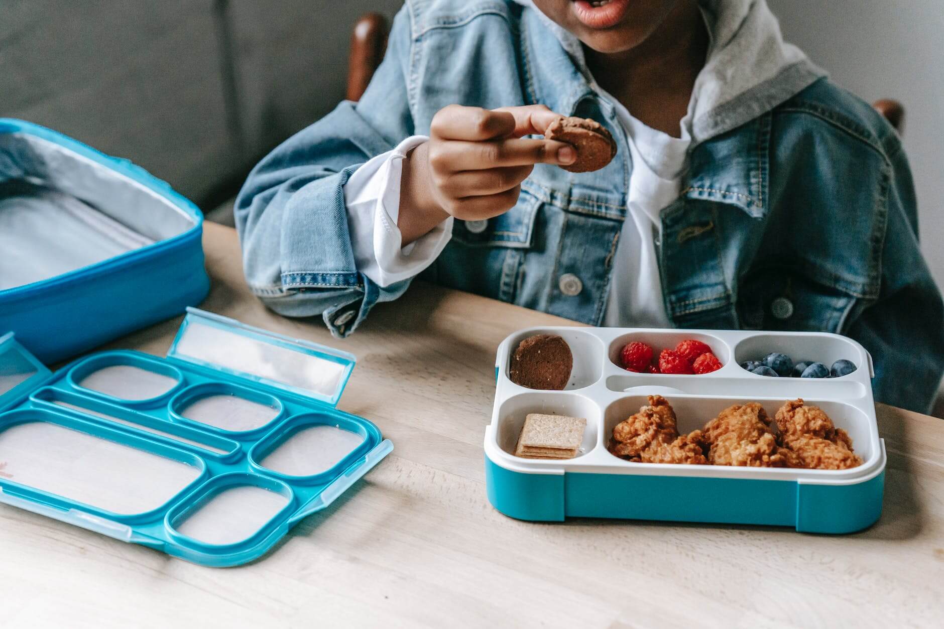 black boy in denim eating tasty breakfast in plastic container