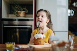 girl in yellow shirt licking icing on spoon