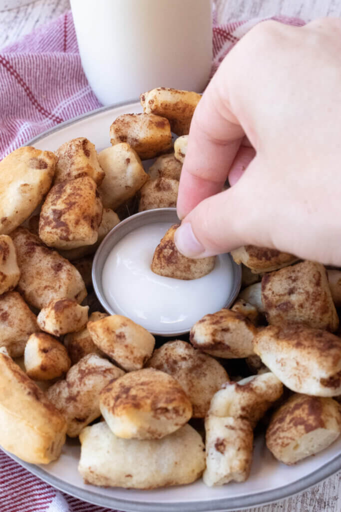 Air fryer cinnamon roll bites dipped in icing