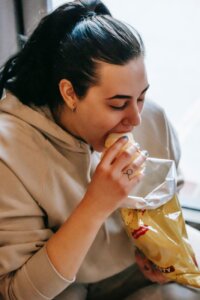 woman in hoodie eating chips