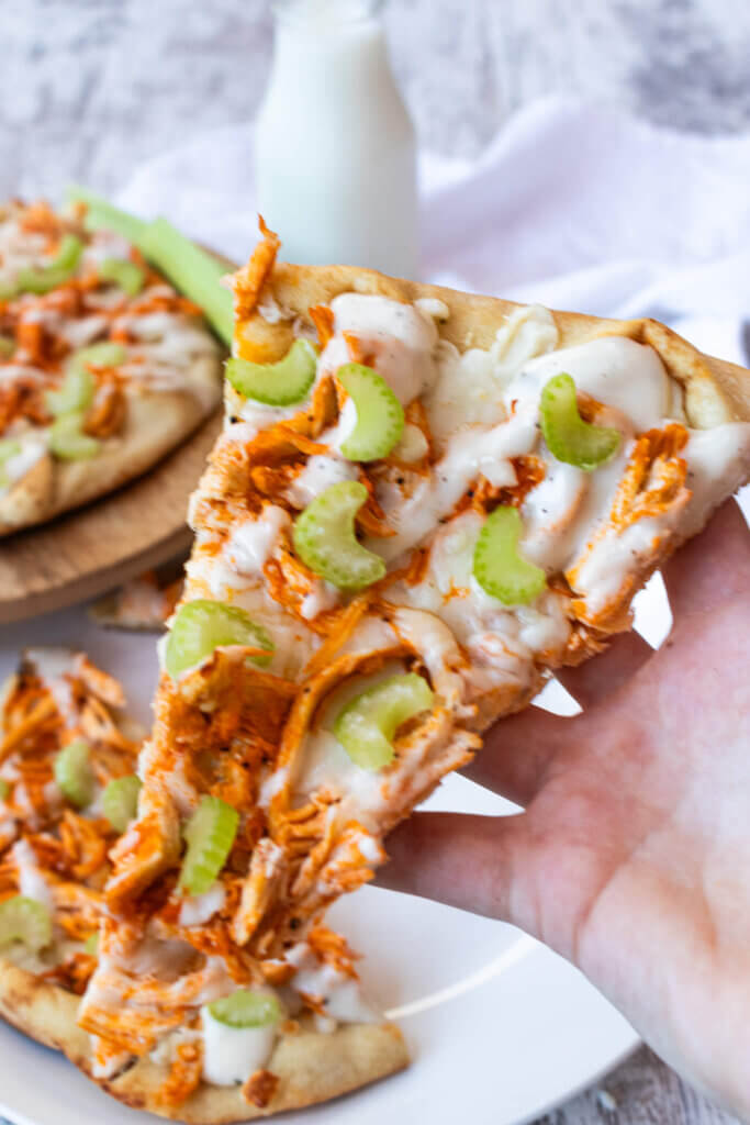 hand holding slice of buffalo chicken flatbread