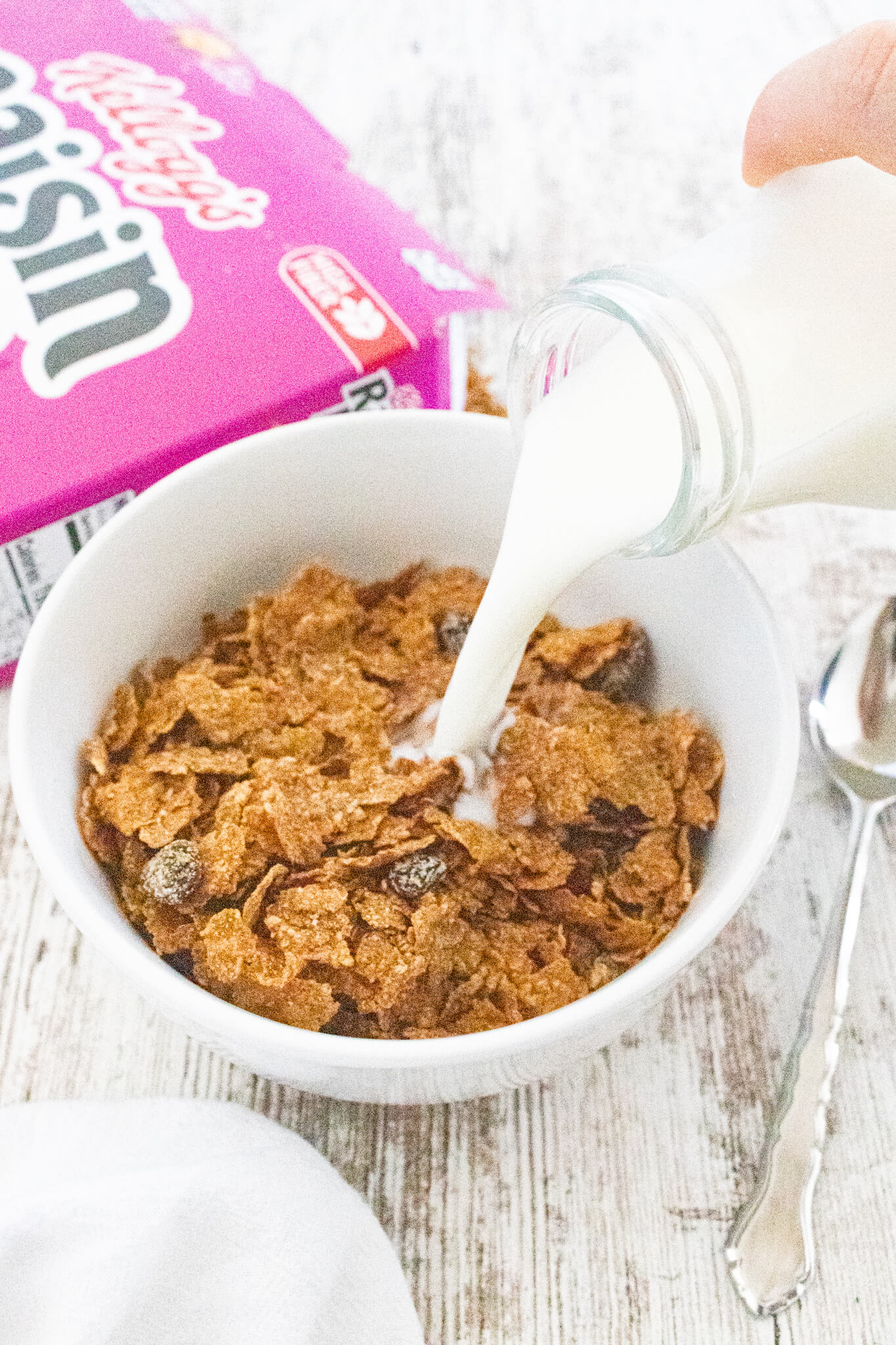 Milk being poured into a bowl of Raisin Bran cereal