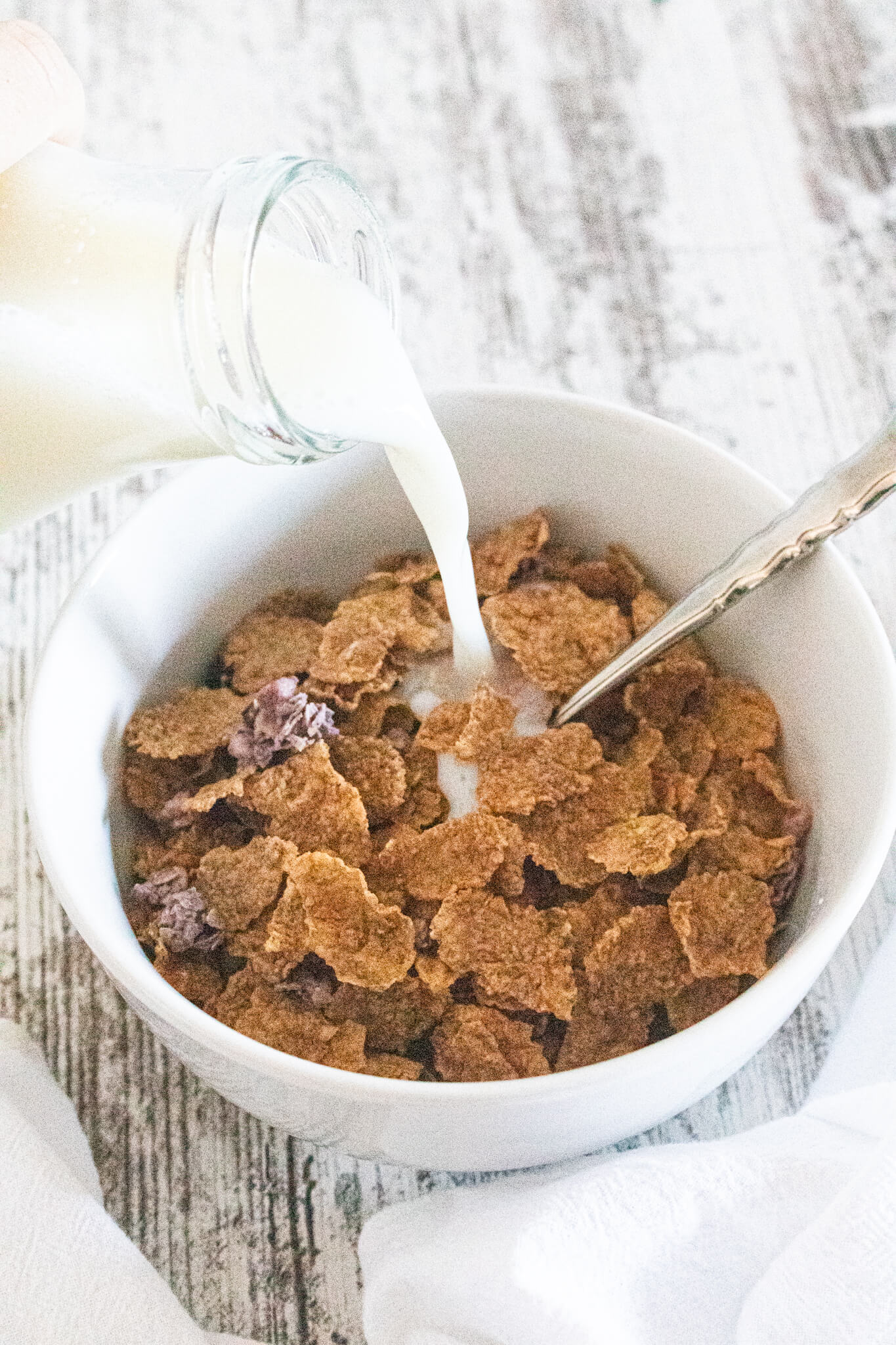 milk being poured into cereal bowl