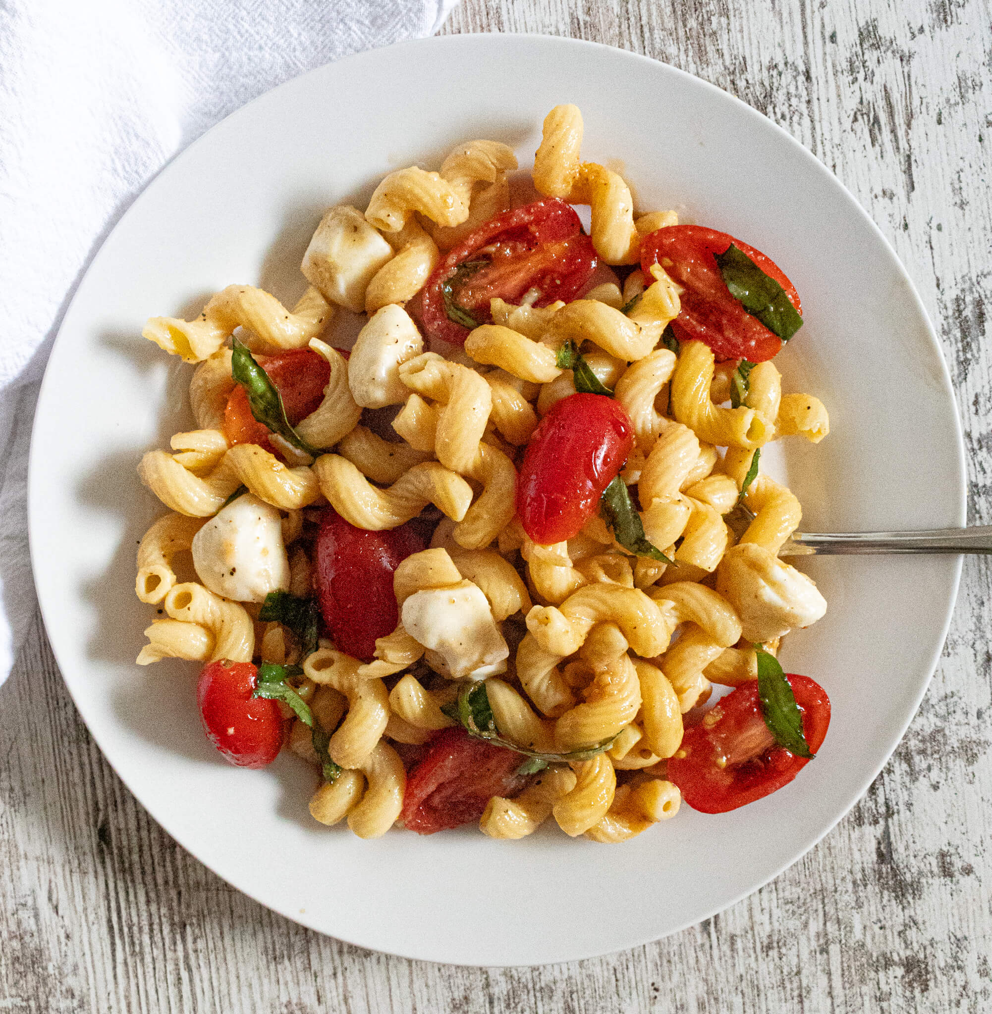 White plate with caprese pasta salad