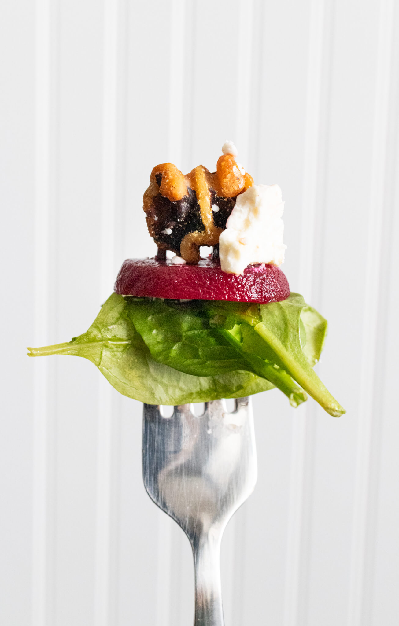 Beet, feta, walnut, and spinach salad on fork